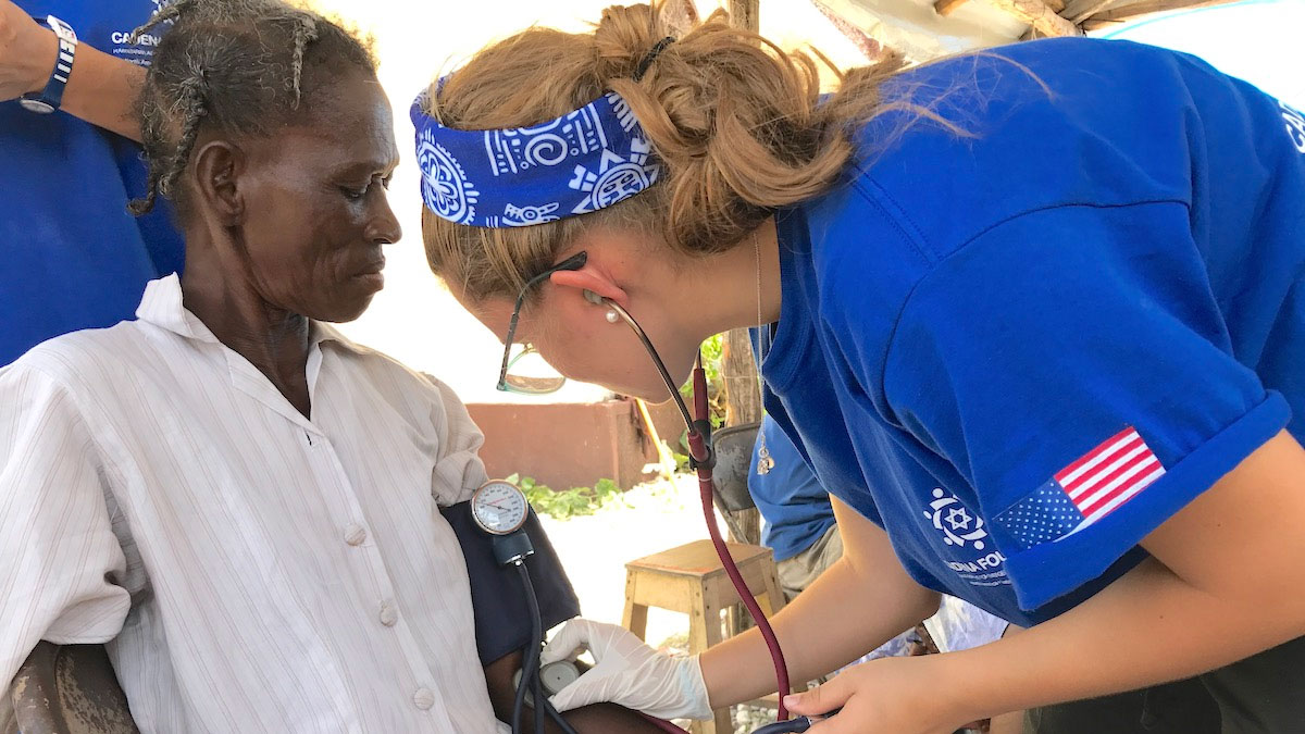 Una doctora voluntaria de CADENA revisa a una paciente durante una misión.