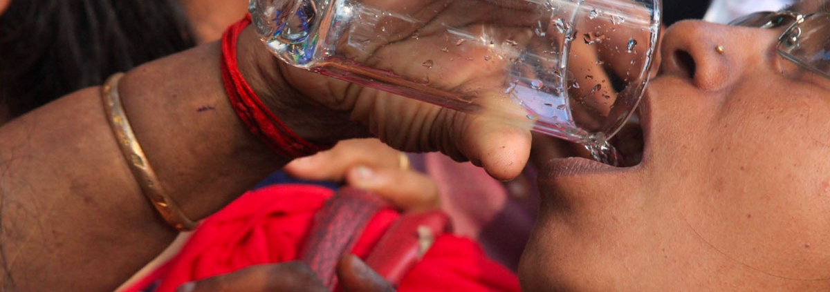 Una mujer toma agua potable gracias a un filtro de agua de CADENA.