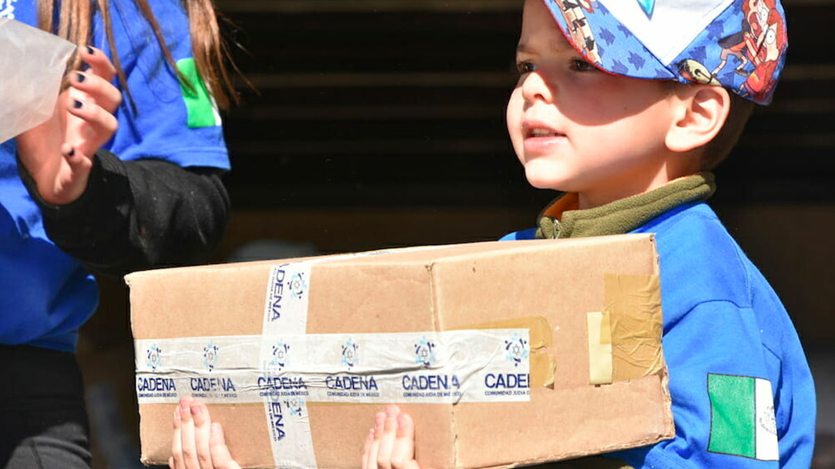 Niño voluntario carga caja con ayuda durante la misión de CADENA a Xochicuautla.